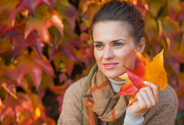 Portrait of thoughtful young woman with autumn leafs in front of — Stock Photo, Image