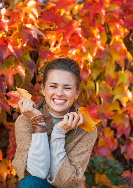 Porträtt av leende ung kvinna framför höst lövverk — Stockfoto