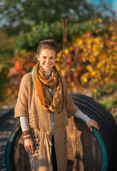 Portrait of smiling young woman standing near wooden barrel in a — Stock Photo, Image