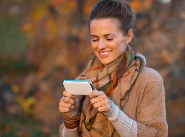 Nahaufnahme einer jungen Frau an einem Herbstabend im Freien, die SMS schreibt — Stockfoto