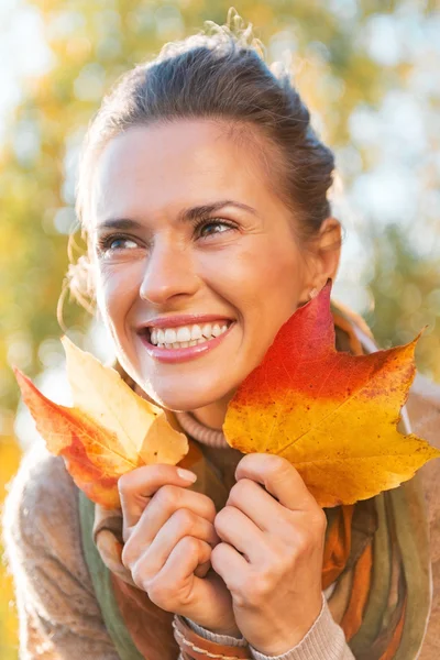 Portrait de jeune femme heureuse avec des feuilles d'automne à l'extérieur — Photo