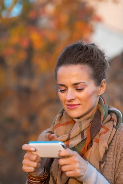 Porträt einer jungen Frau an einem Herbstabend im Freien, die SMS schreibt — Stockfoto