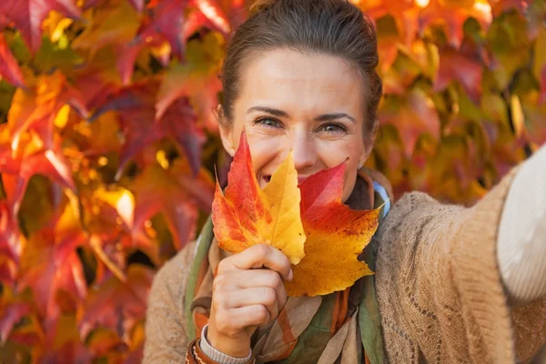 Happy young woman hiding behind leaf while making selfie in fron — Stock Photo, Image