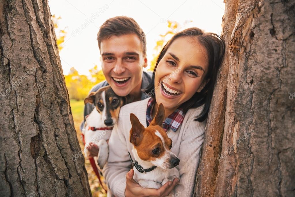 Portrait of happy young couple with dogs outdoors in autumn park