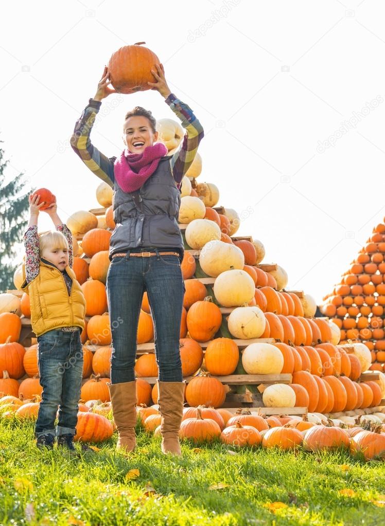 Happy mother and child rising pumpkin up in front of pumpkin pir