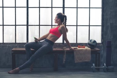 Fit woman in workout gear sitting in profile in loft gym