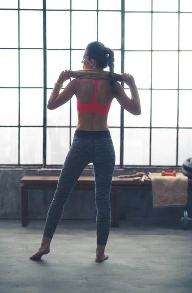 Rear view of fit woman holding towel across shoulders in gym — 스톡 사진
