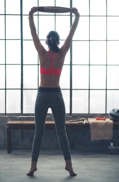 Rear view of woman looking out window using towel to stretch — 스톡 사진