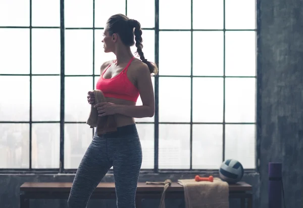 Woman looking over shoulder holding towel in city loft gym — 스톡 사진