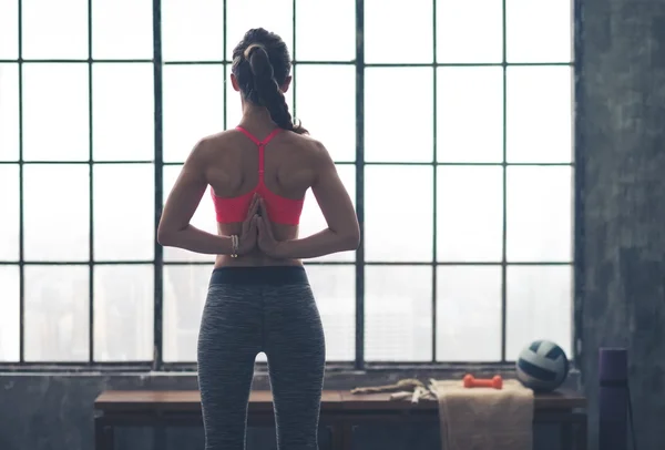 Rear view of woman with hands clasped behind back in yoga pose — 스톡 사진