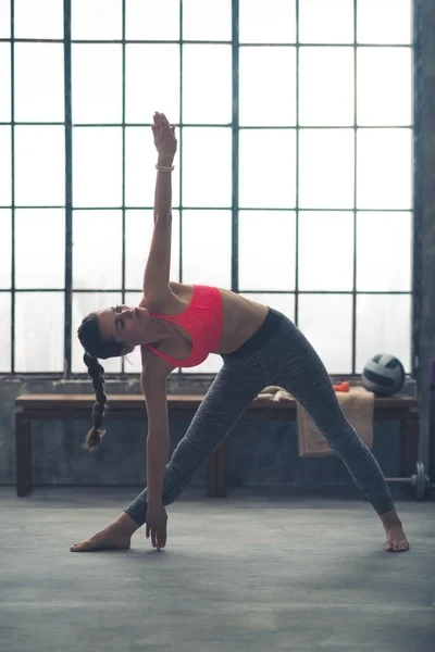 Fit woman in loft gym doing extended triangle pose