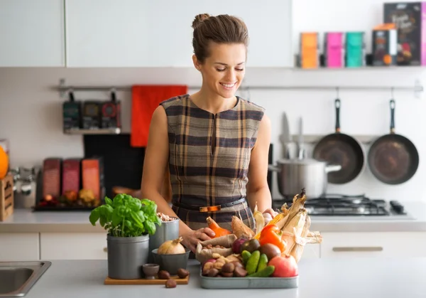 Lachende vrouw in keuken sorteren najaar groenten — Stockfoto