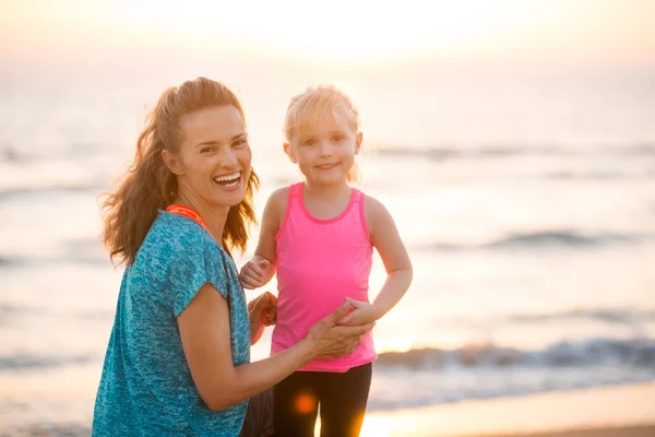 Portrait of young mother and daughter in workout gear on beach — Stock fotografie