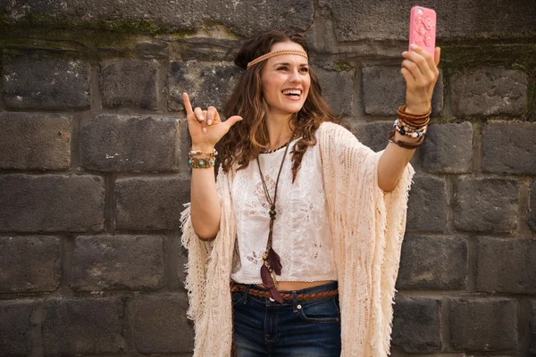 Счастливая молодая женщина у каменной стены делает селфи — стоковое фото