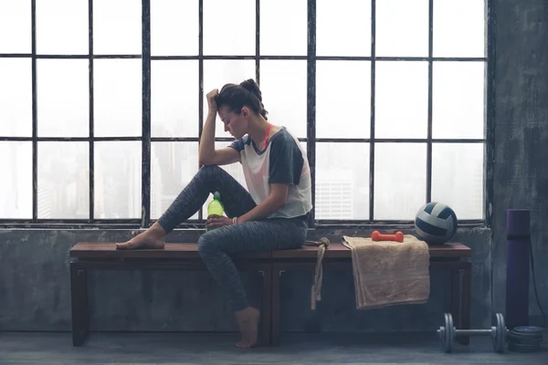 Stanco, donna in forma a riposo testa a mano seduto in palestra soppalco — Foto Stock