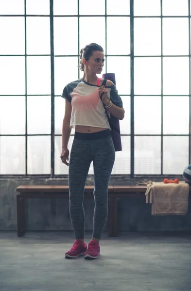 Fit woman in workout gear standing in loft gym looking sideways — 스톡 사진