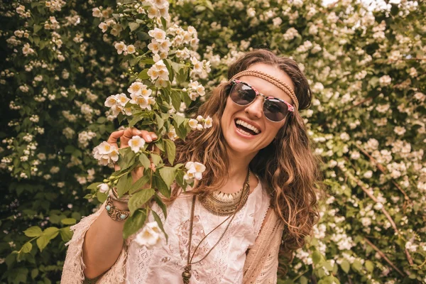 Lachende Boheemse jonge vrouw met tak van bloemen — Stockfoto