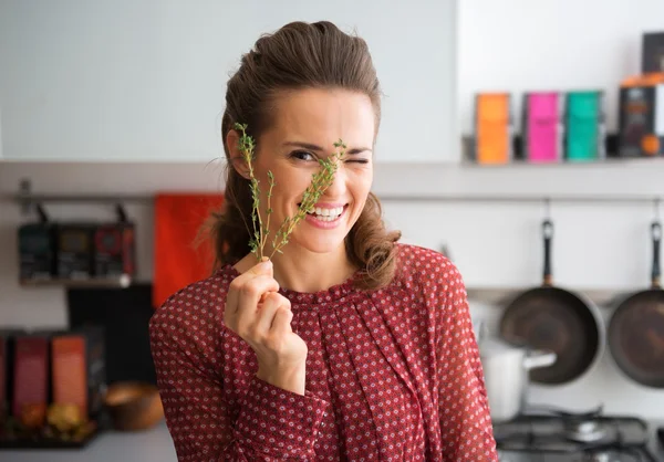 Smiling woman peeking through fresh sprig of thyme — Stock Photo, Image