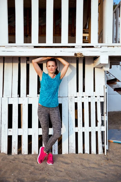 Вмістити жінку, що стоїть у тренувальному спорядженні на пляжному будинку — стокове фото