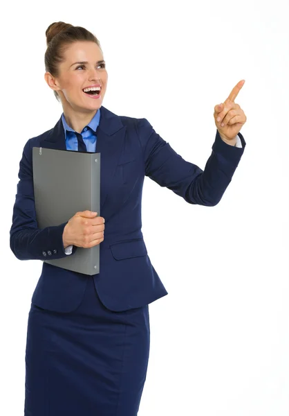 Happy businesswoman holding file, pointing upwards, and smiling — Stock Photo, Image