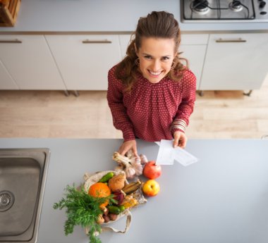 From above, woman smiling in kitchen with fall fruit and veg