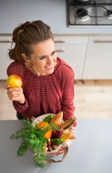 Mulher sorrindo e segurando maçã e outono legumes na cozinha — Fotografia de Stock