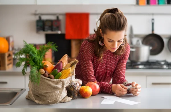 Frau in Küche liest Einkaufsliste mit Einkaufszettel und Quittung — Stockfoto