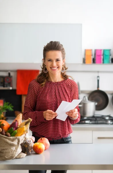 Happy woman with shopping list and bag of fresh produce — Stockfoto