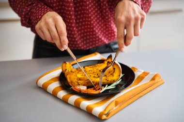 Closeup of hands holding cutlery cutting roasted vegetables