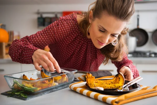 Femme élégante penché sur le plat comme elle sert citrouille — Photo