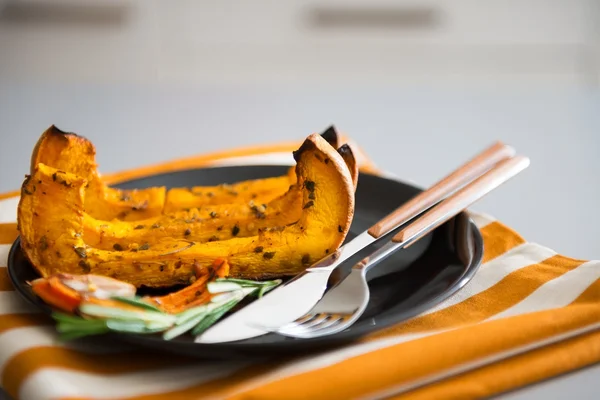 Closeup of pumpkin with herbs and cutlery on dark plate — Stock Photo, Image