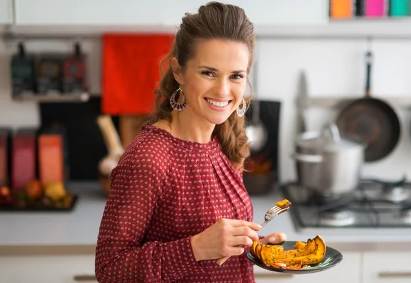 Closeup of woman smiling in kitchen while holding plate of food — Stock Photo, Image