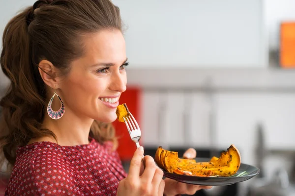 Profile of woman holding bite of roasted pumpkin on a fork