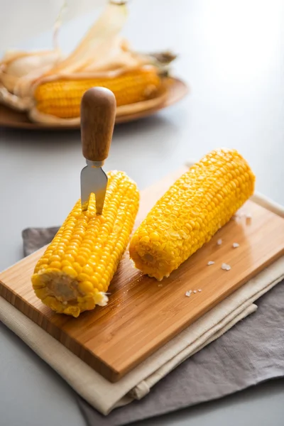 Two corn cobs on a wooden board with a corn skewer — Zdjęcie stockowe