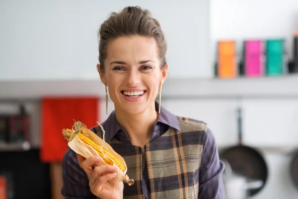 Closeup of smiling woman holding up a corn cob with its husk — Stock Photo, Image