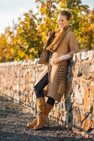 Mujer sonriente con ropa cómoda está de pie en el parque de otoño —  Fotos de Stock