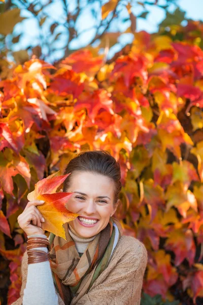 Портрет счастливой женщины с осенними листьями перед листвой — стоковое фото