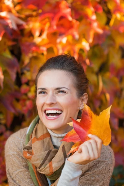 Retrato de mulher alegre com folhas de outono na frente da folhagem — Fotografia de Stock