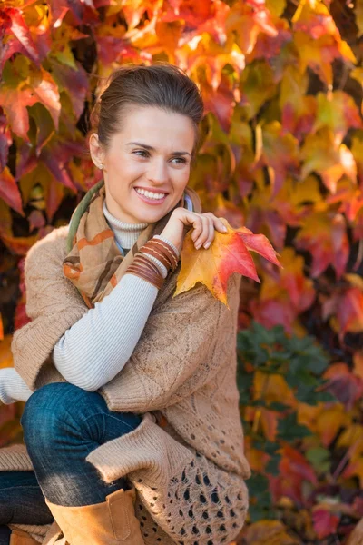 Porträt einer nachdenklichen Frau mit Blättern vor Herbstlaub — Stockfoto