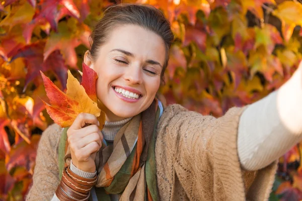 Πορτρέτο της ευτυχισμένος χαλαρή γυναίκα με φθινόπωρο φύλλα λήψης selfie — Φωτογραφία Αρχείου