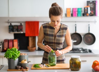 Woman in kitchen preparing dill pickles