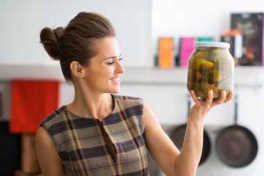 Closeup of woman holding up big jar of freshly-made dill pickles