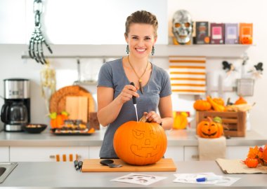 Genç kadın bir kabak Jack-O-Lantern Cadılar Bayramı partisi için oyma