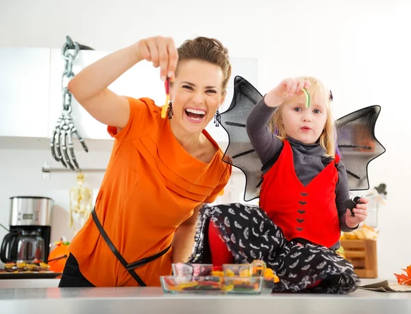 Halloween chica vestida con madre mostrando caramelos de gusano gomoso — Foto de Stock