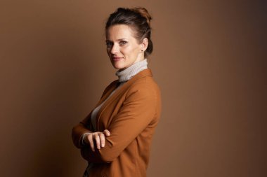 Kahverengi ceketli ve gri balıkçı yakalı orta yaşlı bir işkadını kameraya özgüvenli bir gülümseme ile bakar, belden yukarı bu portrede yaklaşılabilir ama profesyonel bir tavır sergiler..