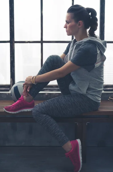 Pensive woman in workout gear looking in profile in loft gym — Stock Photo, Image