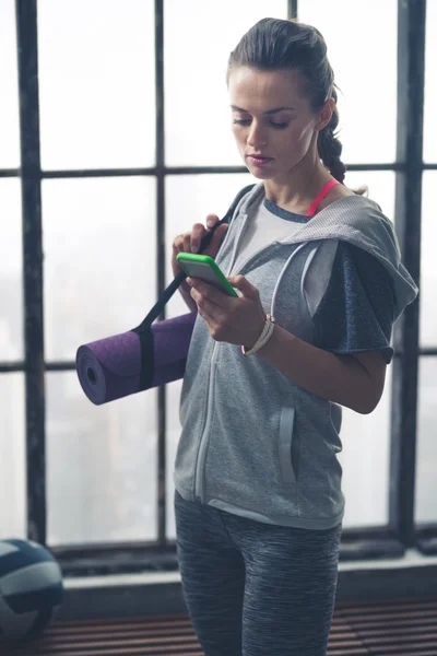 여성 운동에서 휴대 전화를 확인 하는 로프트 체육관 장비 — 스톡 사진