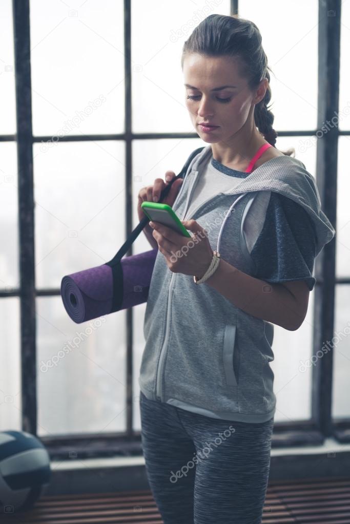 Woman In Workout Gear In Loft Gym Checking Mobile Phone Stock Photo C Citalliance