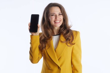 Bu görüntüde, canlı sarı ceketli, akıllı telefonu tutarken kendine güvenen profesyonel bir kadın var. Raporda modern teknoloji, iletişim ve ticari yenilikler vurgulanıyor.