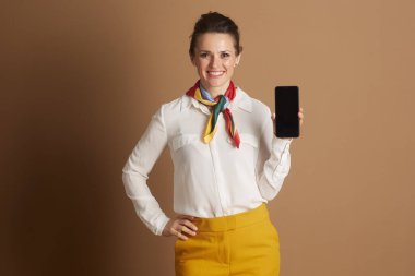 Beyaz gömlekli, kendine güveni tam profesyonel bir kadın ve renkli atkı, akıllı bir telefonla modern iletişim, iş teknolojisi ve dijital bağlantıyı somutlaştırıyor..